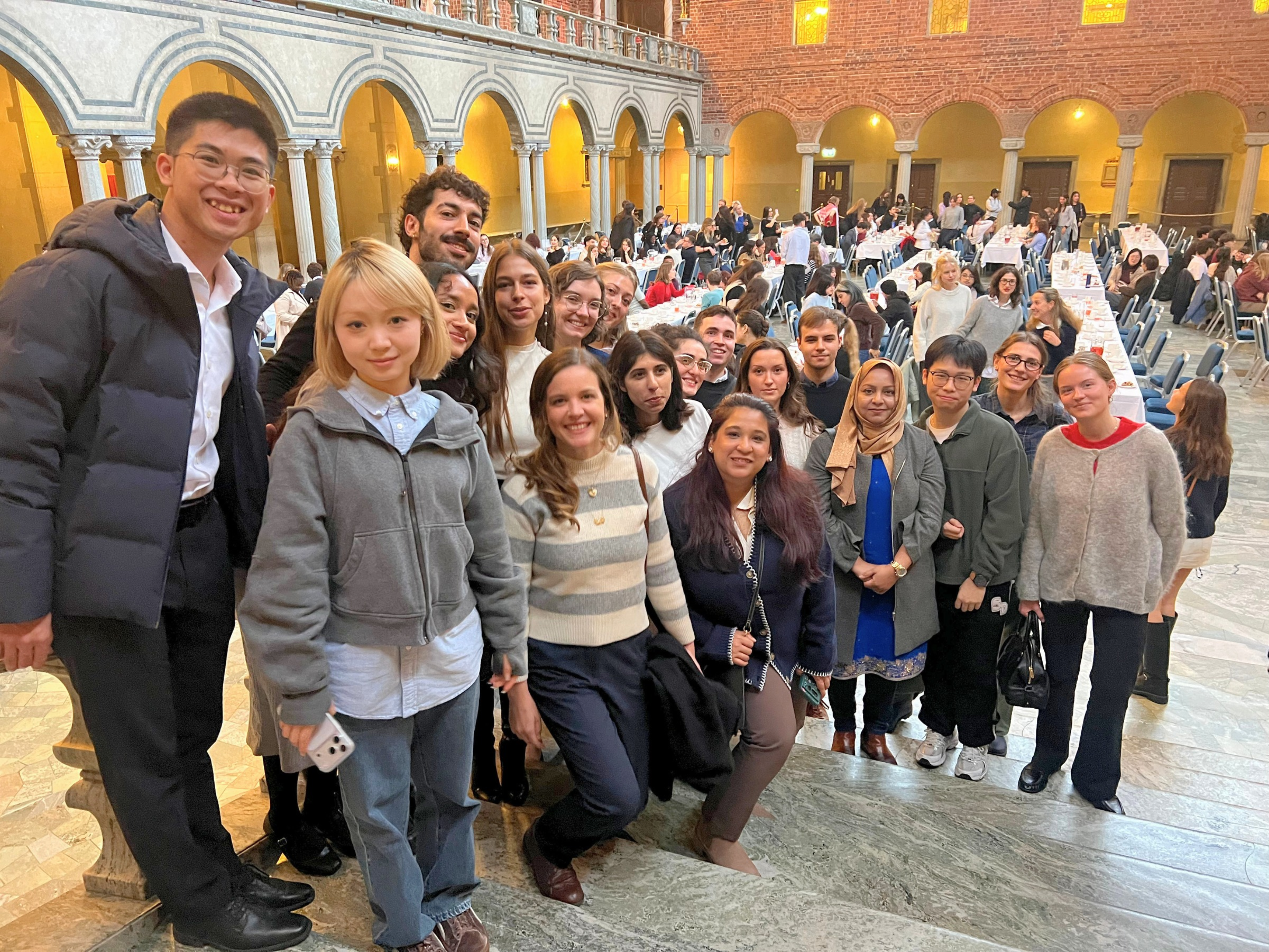 A group of international students posing on the marble staircase at Stockholm City Hall during the 2026 welcome reception.