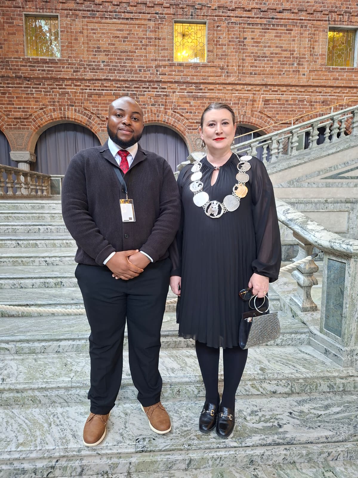 Two attendees posing on the marble staircase at Stockholm City Hall during the international student welcome reception.